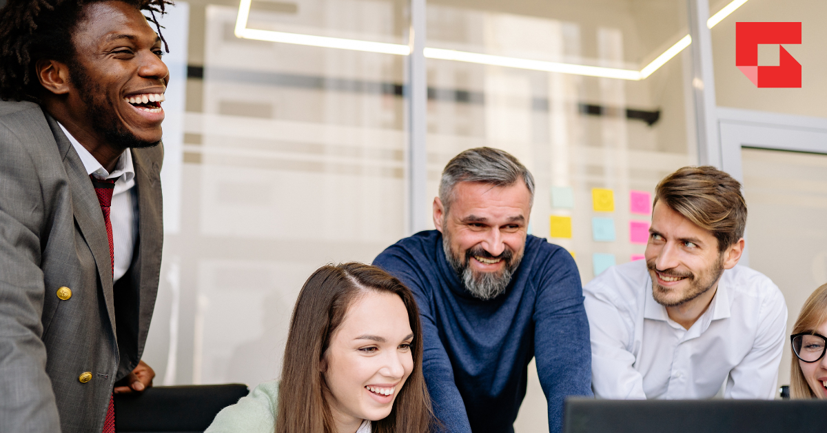 Team of people looking at a computer smiling