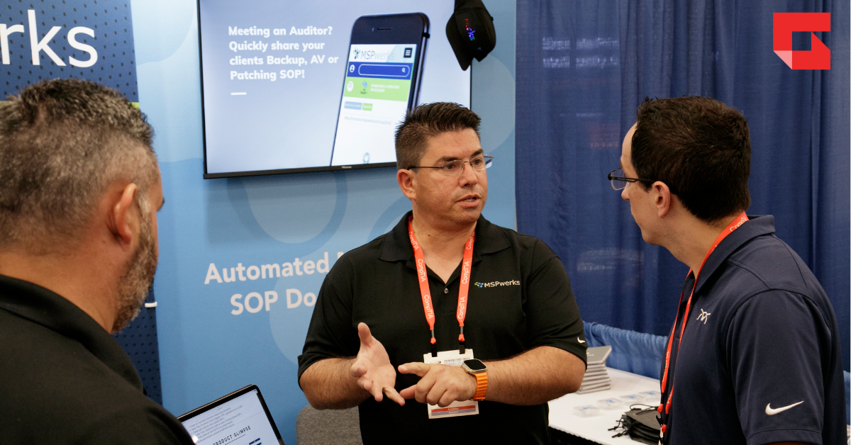 Main talking to two others at a booth during an industry event