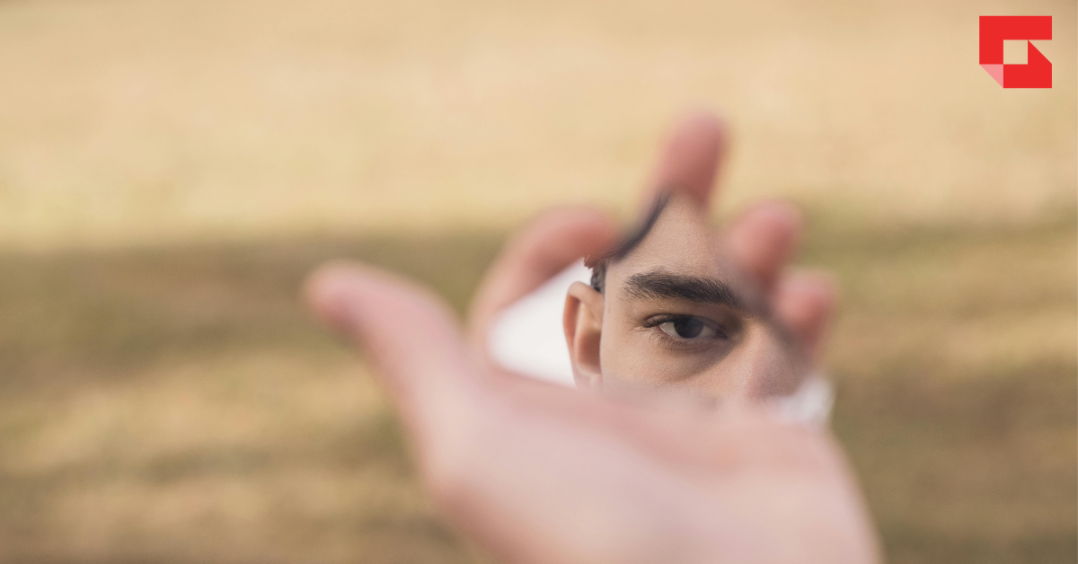 Man looking in a hand-held mirror