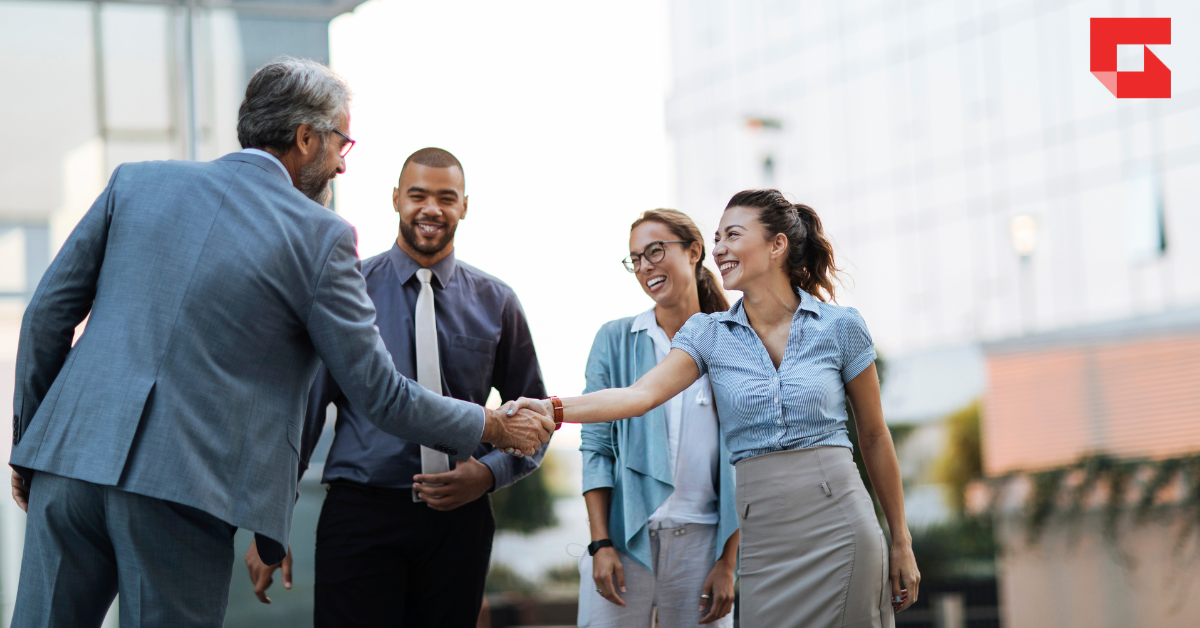 Four people smiling and shaking hands