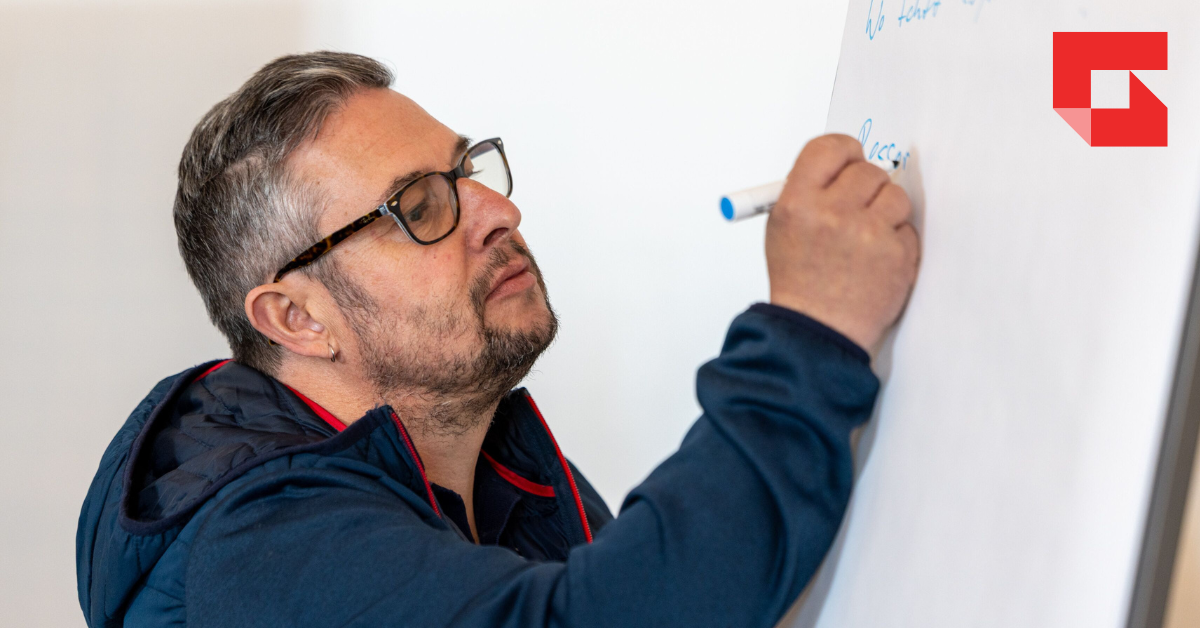 Man writing notes on a large white easel 