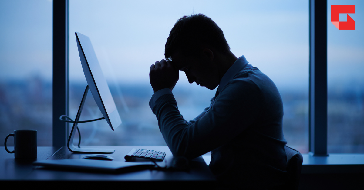 Shadow of man at a computer with his head in his hands.